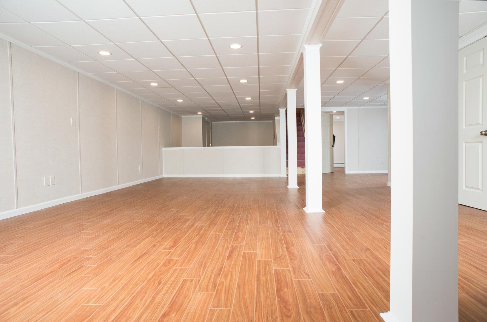 Finished basement space with waterproof wall paneling, ceiling tiles and floor system